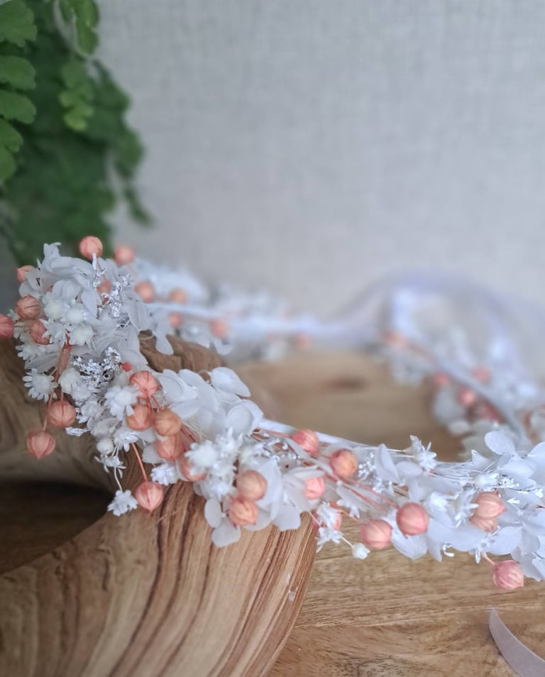 Frost-covered white flowers and coral berries strung on wooden branch and table surface