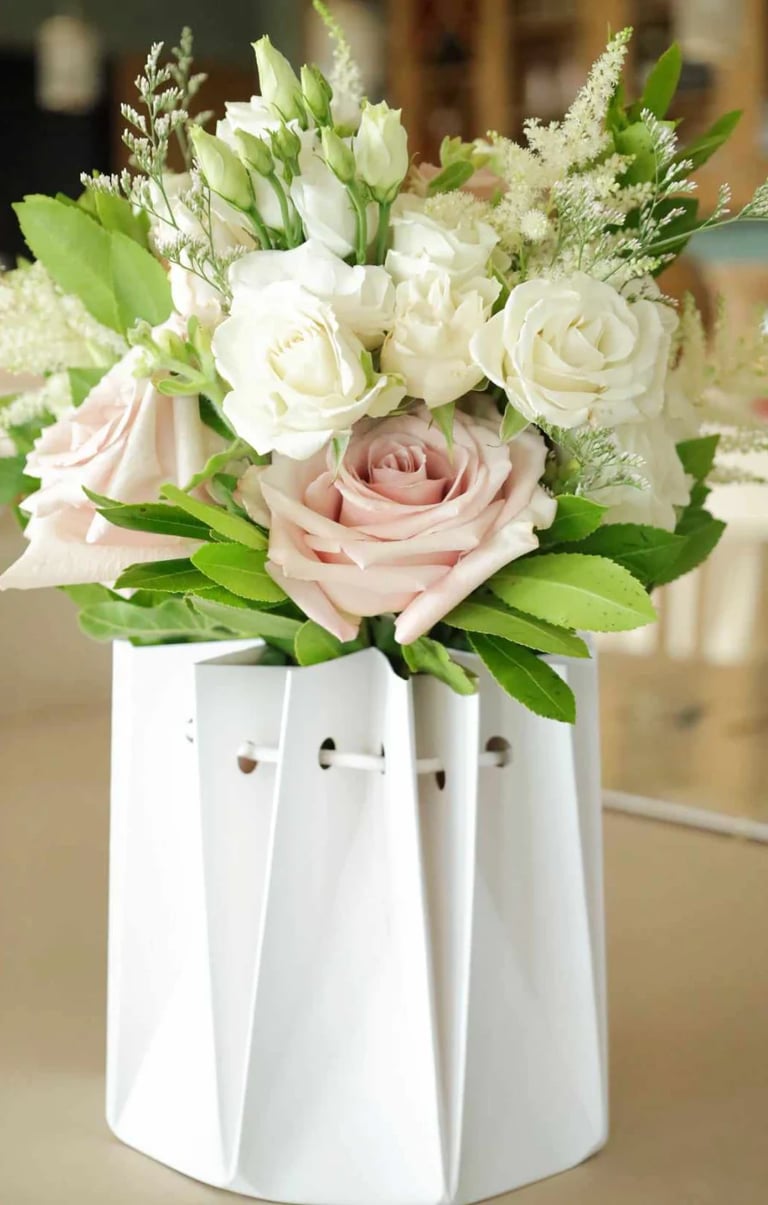 White and pink roses with greenery in a white textured vase