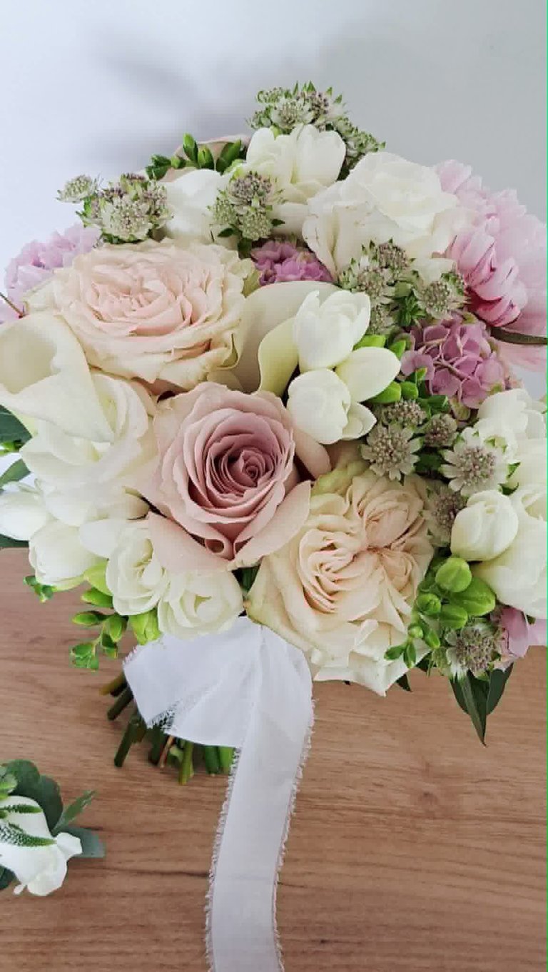Elegant wedding bouquet with cream, pink, and white roses, hydrangeas, and filler flowers