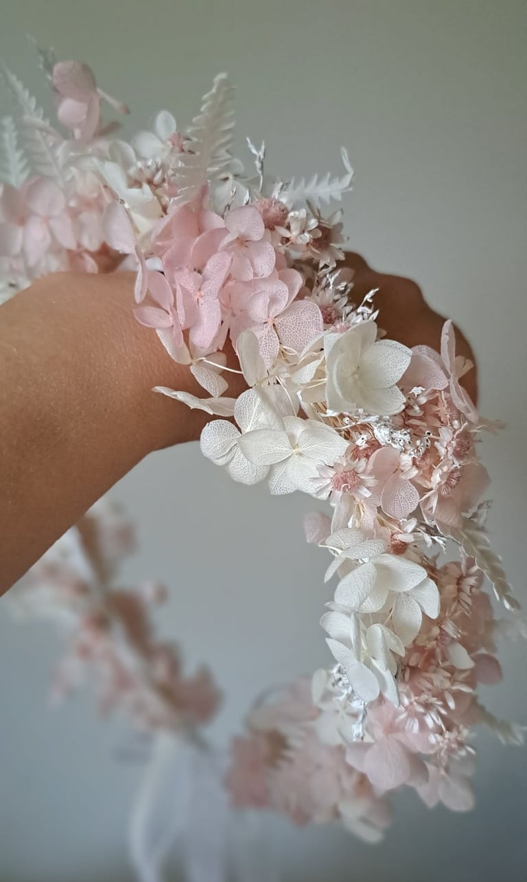 Delicate bridal bracelet featuring dried flowers in pink and white hues with fern accents worn on a wrist